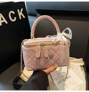Detail of pink quilted box bag with floral metal clasp and lace bow handle