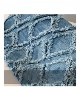 Detailed macro view of denim fabric with quilted rhombus pattern and white fringe texture