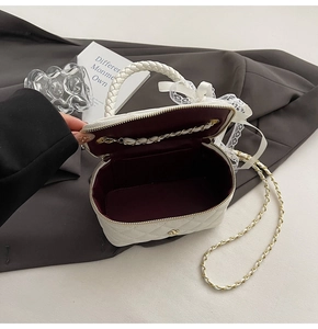 Detailed interior of a white quilted crossbody bag with burgundy lining and lace bow