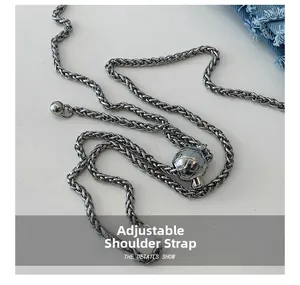 Detail of adjustable silver chain strap with metal ball slider on denim fabric