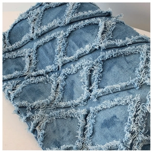 Close-up of blue denim material with quilted fringe patterns and washed texture detail