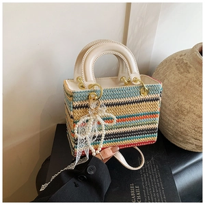 Détail d'un sac à main tissé coloré avec nœud en dentelle blanche et perles décoratives