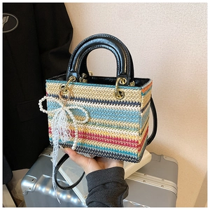 Détail du sac tressé arc-en-ciel avec noeud en dentelle perlée et boucles dorées