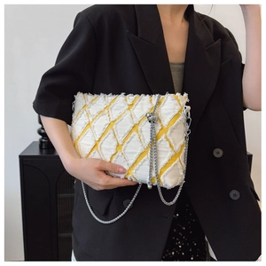 Detail of yellow denim woven crossbody bag with diamond texture and silver chain