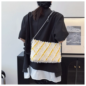 Detail of yellow denim crossbody bag with white diamond quilting and silver chain strap