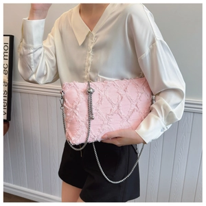 Detail of pink denim underarm bag with diamond weave fringe and silver chain strap