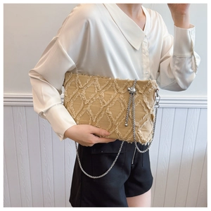 Close-up of khaki canvas shoulder bag with fringed diamond pattern and silver chain