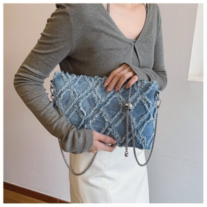 Detail of light blue denim bag featuring frayed diamond pattern and silver chain strap