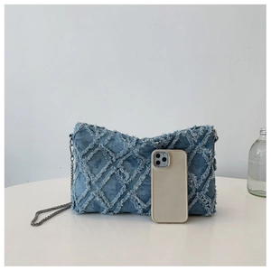 Detailed macro view of blue denim shoulder bag featuring quilted frayed edge patterns
