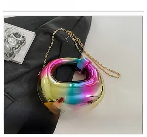 Detail of iridescent geometric hard shell evening bag with golden chain on grey blazer