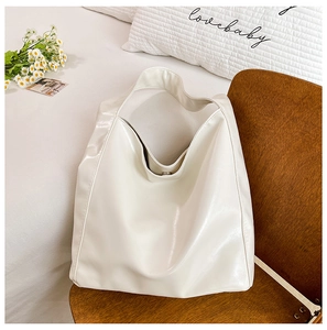 Chic beige large capacity bucket bag with soft leather finish on a wooden chair
