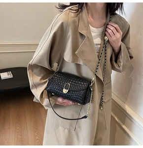 Detail of black woven leather shoulder bag featuring a gold oval metal clasp and chain strap