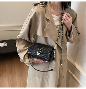 Detail of black woven texture pillow bag with gold chain strap and metal lock closure