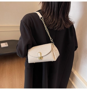 Detail of off-white woven texture handbag with gold metal lock and chain strap on model