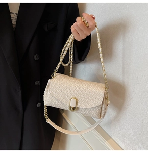Detail of off-white crocodile embossed crossbody bag with gold lock and chain strap