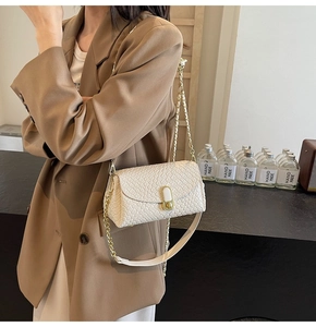 Close-up of a white woven texture shoulder bag featuring a gold chain and minimalist buckle