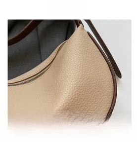 Dettaglio della pelle granulata beige con finiture marroni su una borsa a mezzaluna
