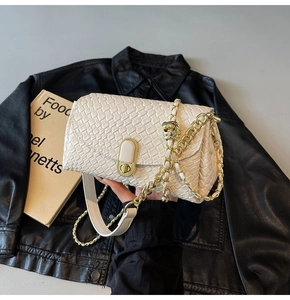 Close-up of white woven shoulder bag with gold chain strap and metallic lock detail