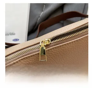 Dettaglio della cerniera dorata e della pelle martellata sulla borsa beige a pieghe