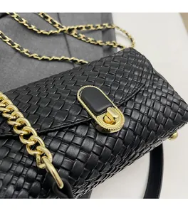 Detailed view of woven black leather texture and gold metal chain strap on handbag