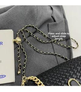 Detail of adjustable gold chain strap with press-to-slide buckle on black woven bag