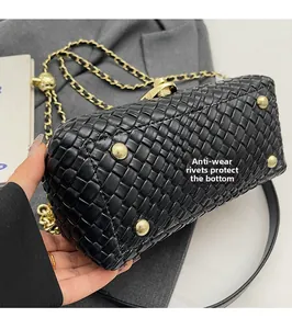 Detailed view of gold anti-wear rivets on the bottom of a black woven leather chain bag