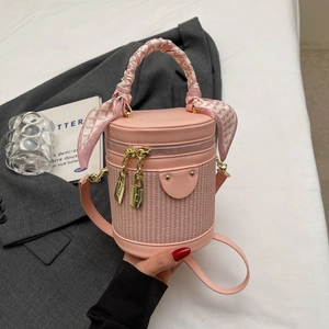 Pink patchwork bucket bag with woven texture, silk scarf handle, and gold zippers