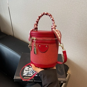 Red leather bucket bag with woven details and silk scarf handle, shown in a trendy urban setting