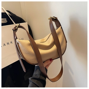 Vista macro di borsa a mezzaluna beige con tracolla in pelle litchi marrone e fibbia