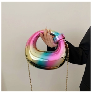 Close-up of a round rainbow gradient acrylic clutch bag with a gold metal chain strap