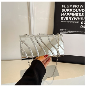 Détail d'une pochette métallique argentée avec une surface rigide à texture diagonale unique