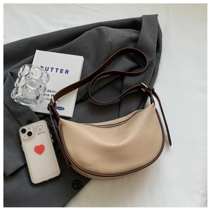 Dettaglio borsa hobo beige a grana di litchi con bordo marrone su blazer grigio