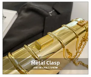 Détail macro du fermoir doré brillant et de la chaîne métallique de la pochette de soirée