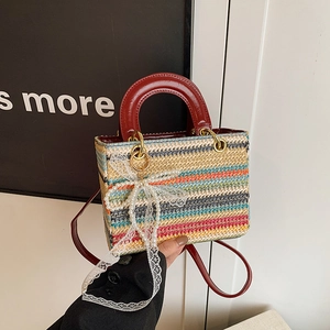 Sac à main tissé coloré avec anses rouges et breloque perle tenu à la main