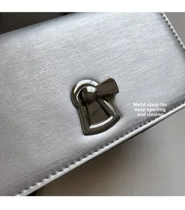 Macro view of silver satin chain bag featuring a polished metal twist lock closure