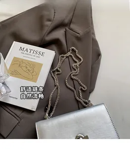 Detail of the silver metallic crossbody bag featuring brushed texture and chain strap