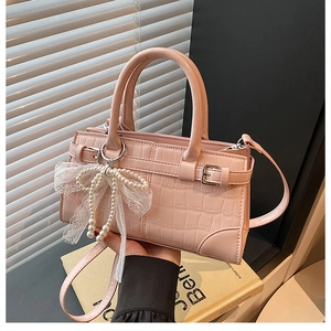 Close-up of pink faux crocodile skin texture and elegant pearl lace bow on hand-held bag
