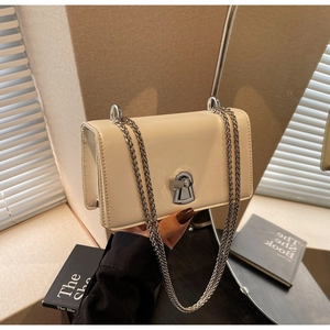 Detail view of a cream chain flap bag with silver hardware and unique keyhole lock