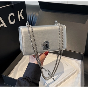 Detail of silver chain bag with metallic texture, keyhole lock and luxury gift box