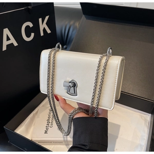 Detailed shot of a white leather crossbody bag with silver buckle and metal chain strap