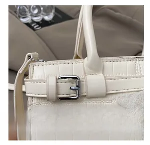 Detailed close-up of the white crocodile pattern faux leather side strap and silver buckle