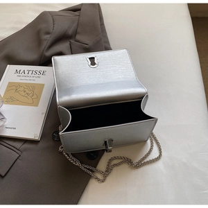 Close-up of silver brushed texture crossbody bag with metal lock and chain strap