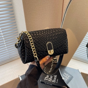 Minimalist black woven shoulder bag with gold chain strap and metallic turn-lock closure