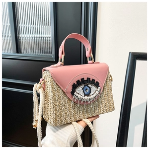 Macro detail of hand-woven straw bag with evil eye beadwork and pink leather flap