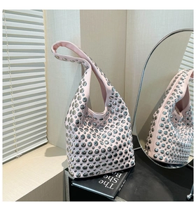Detail of pink hobo bag with silver metallic studs against minimalist indoor backdrop