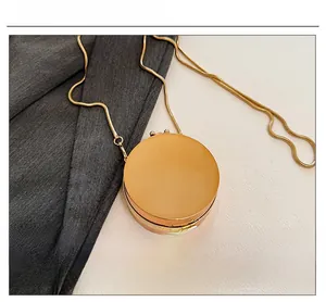 Detailed view of mini round acrylic bag in gold with a sleek metallic snake chain strap