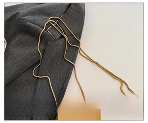 Detail of elegant gold snake chain strap on a metallic mini bag with grey fabric texture