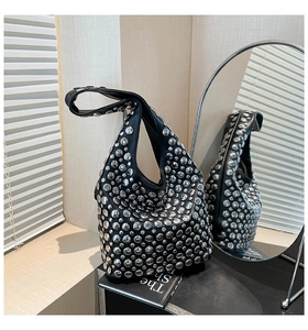 Close-up of black hobo bag featuring polished silver stud rivets and a wide shoulder strap