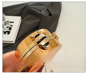 Detail of golden mirror clutch bag with a decorative bee-shaped metal clasp and chain