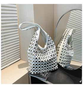 Detail of white hobo bag with silver metallic studs and rivets in a modern mirror setting